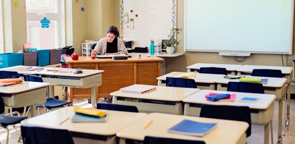 teacher-at-desk-empty-classroom-getty-600x292-1